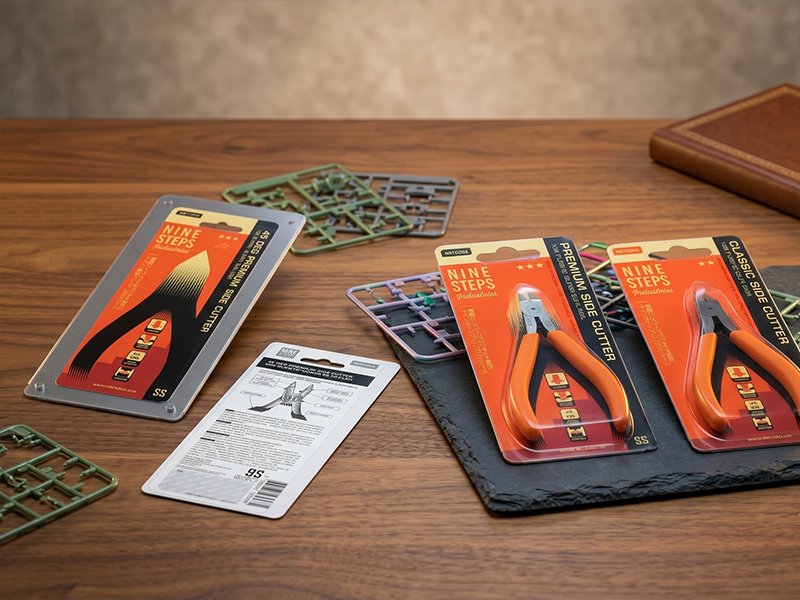 Nine Steps hand-tool packaging arranged flat on a wooden table beside model kit parts.